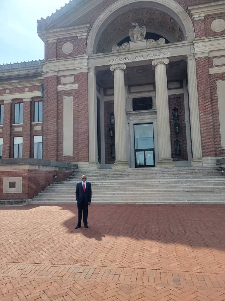 A man standing in front of the entrance to a brick building