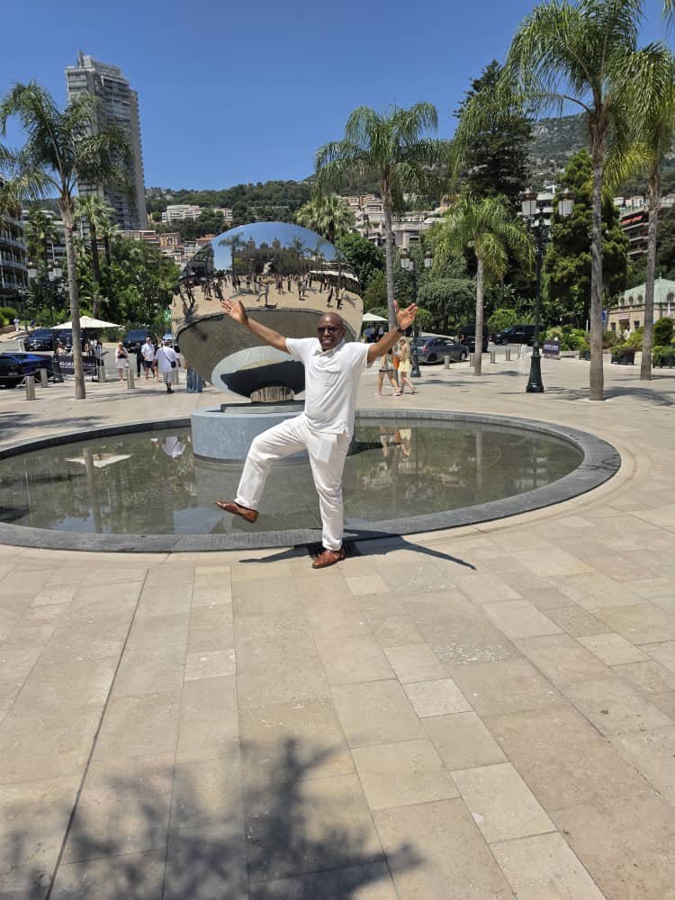 A man in light clothing standing beside a fountain