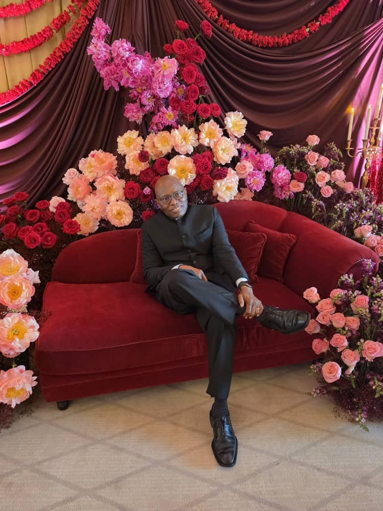 Dshaikh seated at a celebration with floral decorations