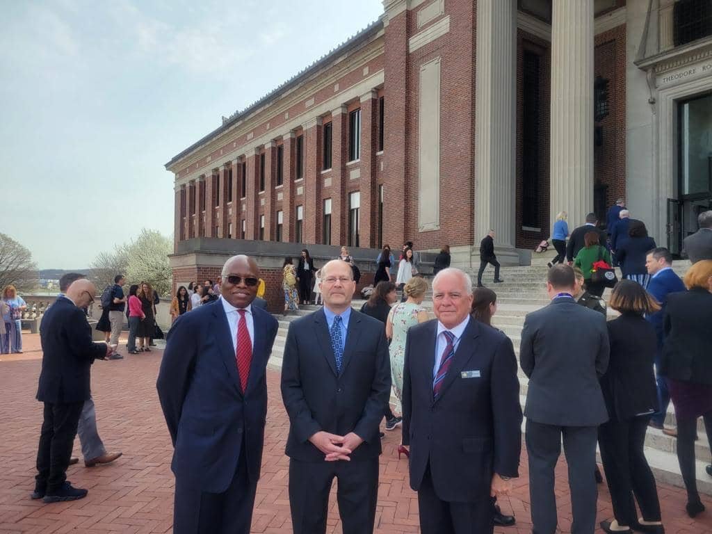 Three men in suits standing outside a brick building