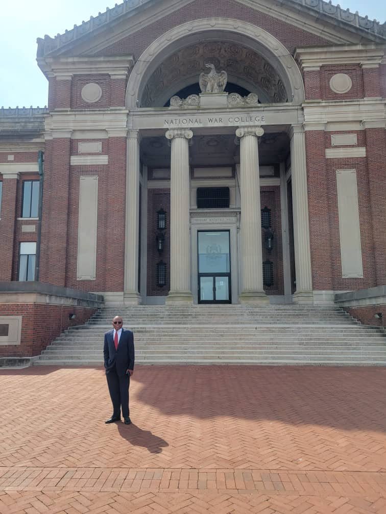 A man standing on the plaza in front of a brick building
